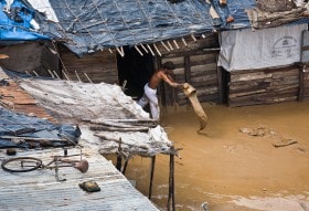 Clearing mud from a make-shift hut along the banks of the Sabarmati river as the water recedes. Ahmedabad India.